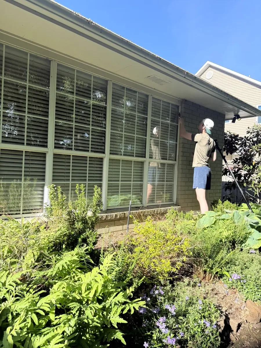 Luma Solutions technician hand-detailing windows at a brick Northwest Arkansas home